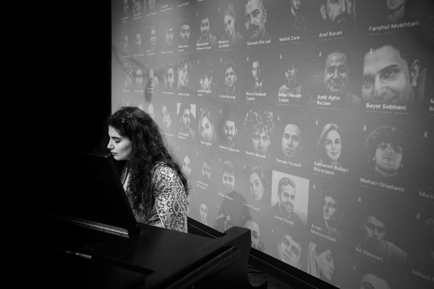 Homa Samiei at the piano in front of a memorial wall